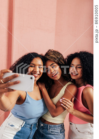 Portrait of three laughing females with curly hair. Happy women having fun together Portrait of three laughing females with curly hair. Happy women having fun together 86910005