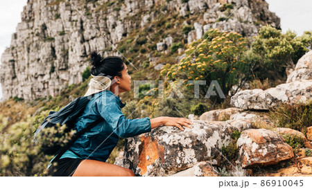 Woman hiker climbing up on a mountain. Young female hiking over extreme terrain. Woman hiker climbing up on a mountain. Young female hiking over extreme terrain. 86910045