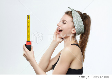 beautiful blonde girl holds a measuring tape in her hands. measurement concept about penis size beautiful blonde girl holds a measuring tape in her hands. measurement concept about penis size 86912166