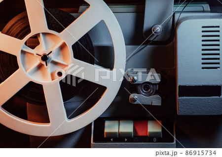 Coils with tape film turning. Analog player. Retro old-fashioned 8mm projector playing movie at 86915734