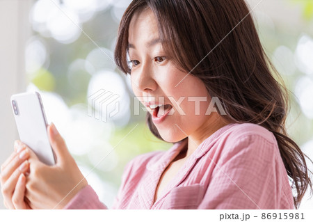 明るい室内でスマホの画面を見る部屋着姿の女性 明るい室内でスマホの画面を見る部屋着姿の女性 86915981