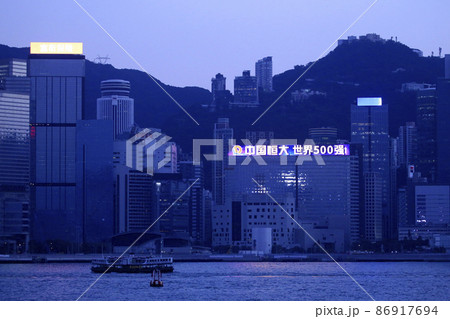 薄暮の香港ビクトリア湾を航行するスターフェリー。奥はビクトリア湾観光船「アクアルナ」 86917694