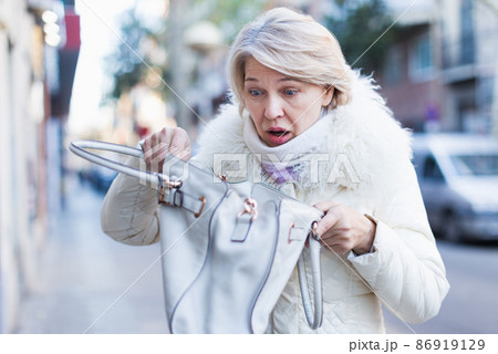 Sad mature woman is standing with empty bag and walking Sad mature woman is standing with empty bag and walking 86919129