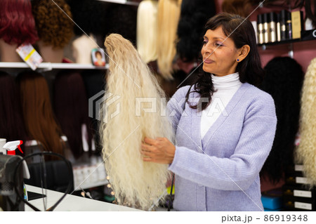 Woman choosing natural wig at specialty boutique 86919348