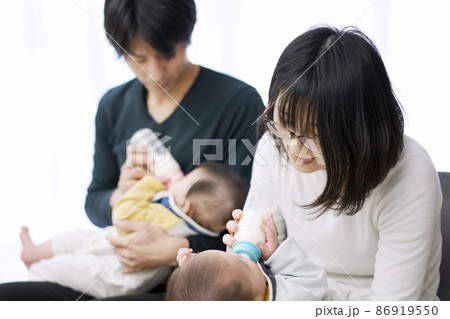 双子の赤ちゃんのミルクをあげるアジア人の両親 86919550