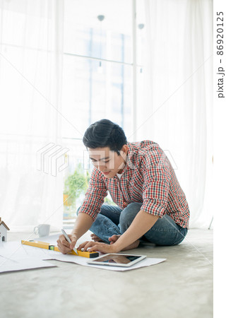 Young handsome male asian architect working at home on the floor. Young handsome male asian architect working at home on the floor. 86920125