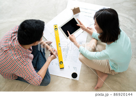 Attractive young asian adult couple looking at house plans. Attractive young asian adult couple looking at house plans. 86920144