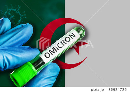 Algeria outbreak of omicron variant. Hand holds a test tube with covid-19 virus omicron in front of Algeria flag 86924726