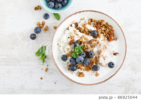 Bowl of granola with fresh blueberry, cottage cheese or curd, yogurt and nuts. Healthy food. Breakfast. Top view 86925044