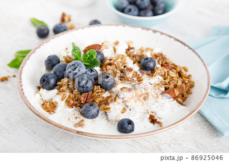 Bowl of granola with fresh blueberry, cottage cheese or curd, yogurt and nuts. Healthy food. Breakfast 86925046