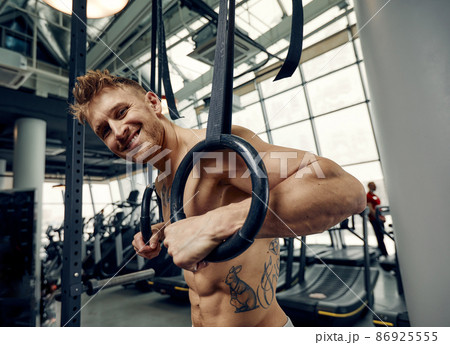Muscle-up exercise young man doing intense cross fit workout at the gym on gymnastic rings. Muscle-up exercise young man doing intense cross fit workout at the gym on gymnastic rings. 86925555