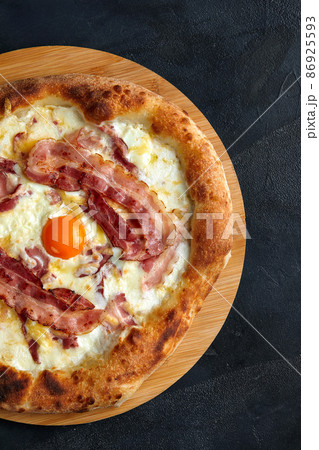 Carbonara pizza with bacon and egg on dark stone background Carbonara pizza with bacon and egg on dark stone background 86925593