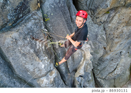 Strong male climber climbing steep wall of rocky mountain. Sportsman overcoming difficult route. Engaging in extreme sports hobby concept. 86930131