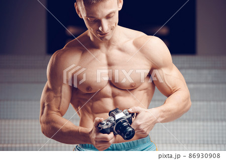 Old-fashioned camera in the hands of a muscular young cameraman 86930908