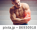 Injured elbow. Young handsome muscular athlete having elbow pain 86930918