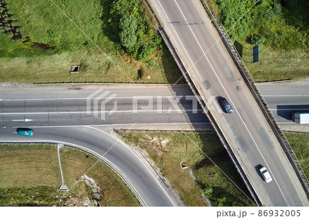 Aerial view of road intersection with fast moving heavy traffic on city streets. Uban transportation during rush hour with many cars and trucks Aerial view of road intersection with fast moving heavy traffic on city streets. Uban transportation during rush hour with many cars and trucks 86932005