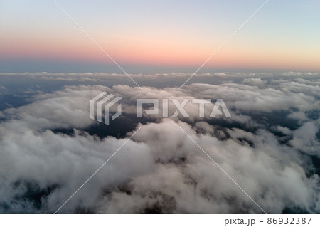 Aerial view from above at high altitude of dense puffy cumulus clouds flying in evening. Amazing sunset from airplane window point of view Aerial view from above at high altitude of dense puffy cumulus clouds flying in evening. Amazing sunset from airplane window point of view 86932387