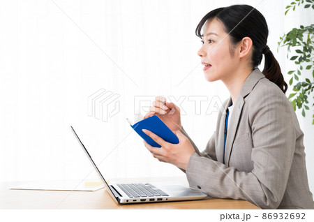 手帳を片手に仕事中の女性 86932692