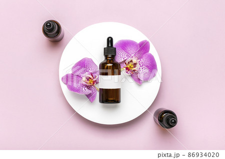 glass cosmetic bottle with moisturizing natural oil, Orchid lie on white podium isolated on pink background Top view Flat lay Eco, bio, zero waste product concept Copy space Mock up 86934020