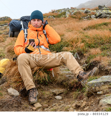 A man with a smartphone travels the mountains, a blogger in the mountains, mobile in the Carpathians. A man with a smartphone travels the mountains, a blogger in the mountains, mobile in the Carpathians. 86934129