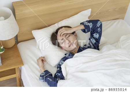 苦しそうな表情で眠るミドルの女性 86935014