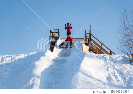 Fun Young woman with snow tubing winter activity, slide from snow hill. Selective focus 86935294