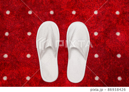 White slippers on red carpet with white dots background White slippers on red carpet with white dots background 86938426