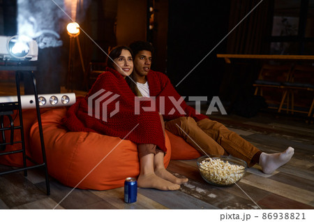 Couple wrapped in blanket watching home projector 86938821