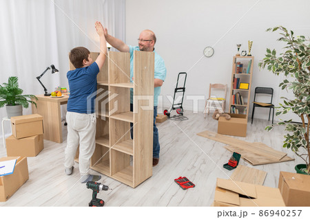 The son and father are happy as they finish assembling the bookcase. 86940257