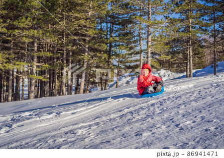 happy and positive little boy enjoying sledding and cold weather outdoor, winter fun activity concept happy and positive little boy enjoying sledding and cold weather outdoor, winter fun activity concept 86941471
