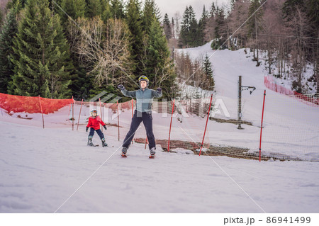 Boy learning to ski, training and listening to his ski instructor on the slope in winter 86941499