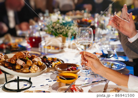 hands with glasses above the festive table 86941500