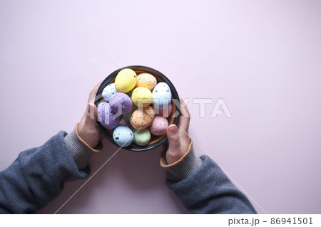 child hand holding a bowl of easter eggs on pink  86941501