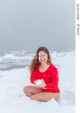 Caucasian woman in a red tracksuit plays snowballs. 86941656