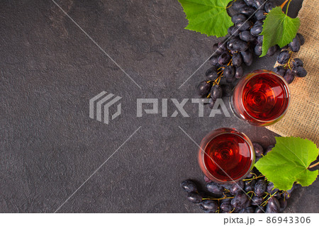 Glasses of red wine and blue grape on black background top view. Glasses of red wine and blue grape on black background top view. 86943306