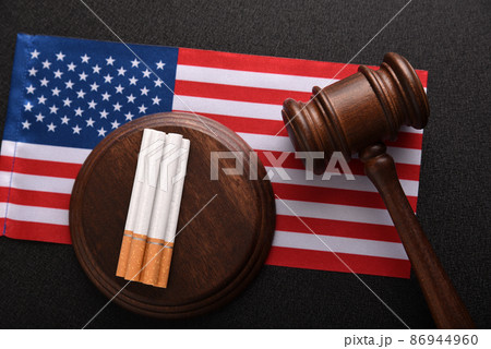 Tobacco law in United States of America. Cigarettes, wooden Judge gavel and flag of USA. Tobacco control act Tobacco law in United States of America. Cigarettes, wooden Judge gavel and flag of USA. Tobacco control act 86944960
