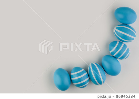 Corner border of blue striped Easter eggs over a light background.  86945234