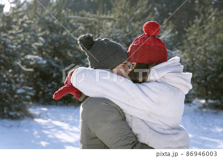 Happy lovers kissing in winter forest. Young couple in love walking outside Happy lovers kissing in winter forest. Young couple in love walking outside 86946003