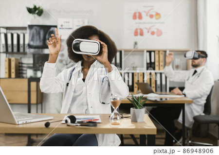 Multiethnic medical workers in VR headset sitting at cabinet 86948906