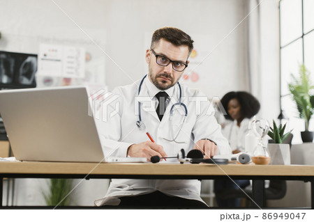 Doctor writing prescription to patient during video call Doctor writing prescription to patient during video call 86949047