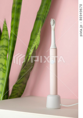 New modern ultrasonic toothbrushes. Dental care supplies with green leaves on pink pastel background. Oral hygiene, gum health, healthy teeth. Dental products Ultrasonic vibration toothbrush. New modern ultrasonic toothbrushes. Dental care supplies with green leaves on pink pastel background. Oral hygiene, gum health, healthy teeth. Dental products Ultrasonic vibration toothbrush. 86949670