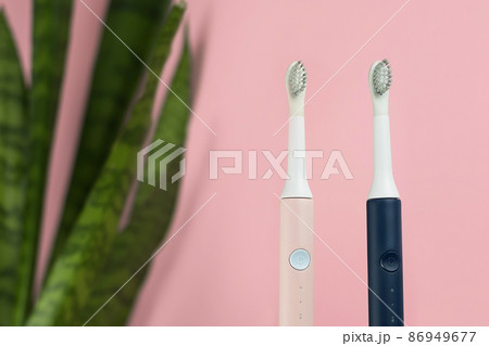New modern ultrasonic toothbrushes. Dental care supplies with green leaves on pink pastel background. Oral hygiene, gum health, healthy teeth. Dental products Ultrasonic vibration toothbrush. New modern ultrasonic toothbrushes. Dental care supplies with green leaves on pink pastel background. Oral hygiene, gum health, healthy teeth. Dental products Ultrasonic vibration toothbrush. 86949677