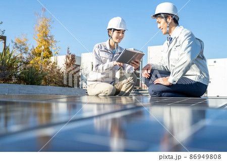 ソーラーパネルをチェックするビジネスマンと女性作業員 86949808