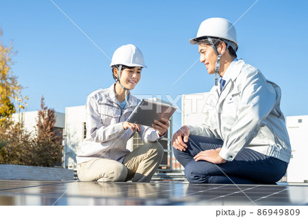 ソーラーパネルをチェックするビジネスマンと女性作業員 ソーラーパネルをチェックするビジネスマンと女性作業員 86949809