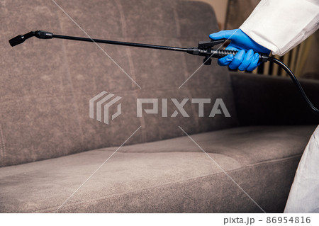 An exterminator in work clothes sprays pesticides with a spray gun. Fight against insects in apartments and houses. Disinsection of the premises An exterminator in work clothes sprays pesticides with a spray gun. Fight against insects in apartments and houses. Disinsection of the premises 86954816