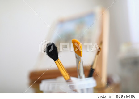 Painting brushes and easel stand in the room 86956486