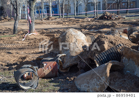Construction Debris. Debris of concrete and plastic pipes at the construction site. The area is fenced with red and white tape. 86959401