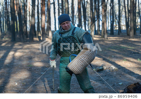 Portrait of a canine instructor training dogs for protective guard duty. A mature man holds a baton and put on a bite sleeve in front of a sheepdog. Training of service dogs Portrait of a canine instructor training dogs for protective guard duty. A mature man holds a baton and put on a bite sleeve in front of a sheepdog. Training of service dogs 86959406