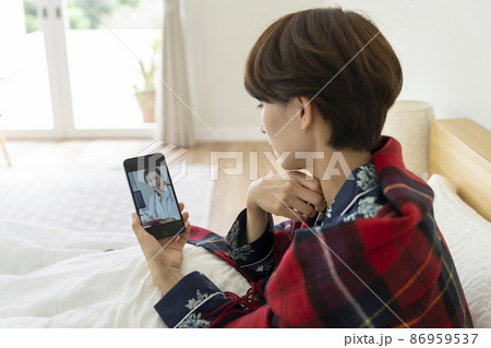 スマートフォンでオンライン診療を受けるミドル女性　イメージ 86959537