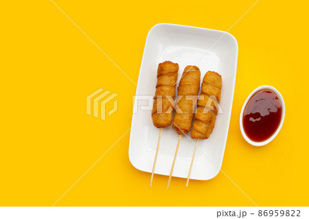 Fried dough snacks wrapped sausage on yellow background. Fried dough snacks wrapped sausage on yellow background. 86959822